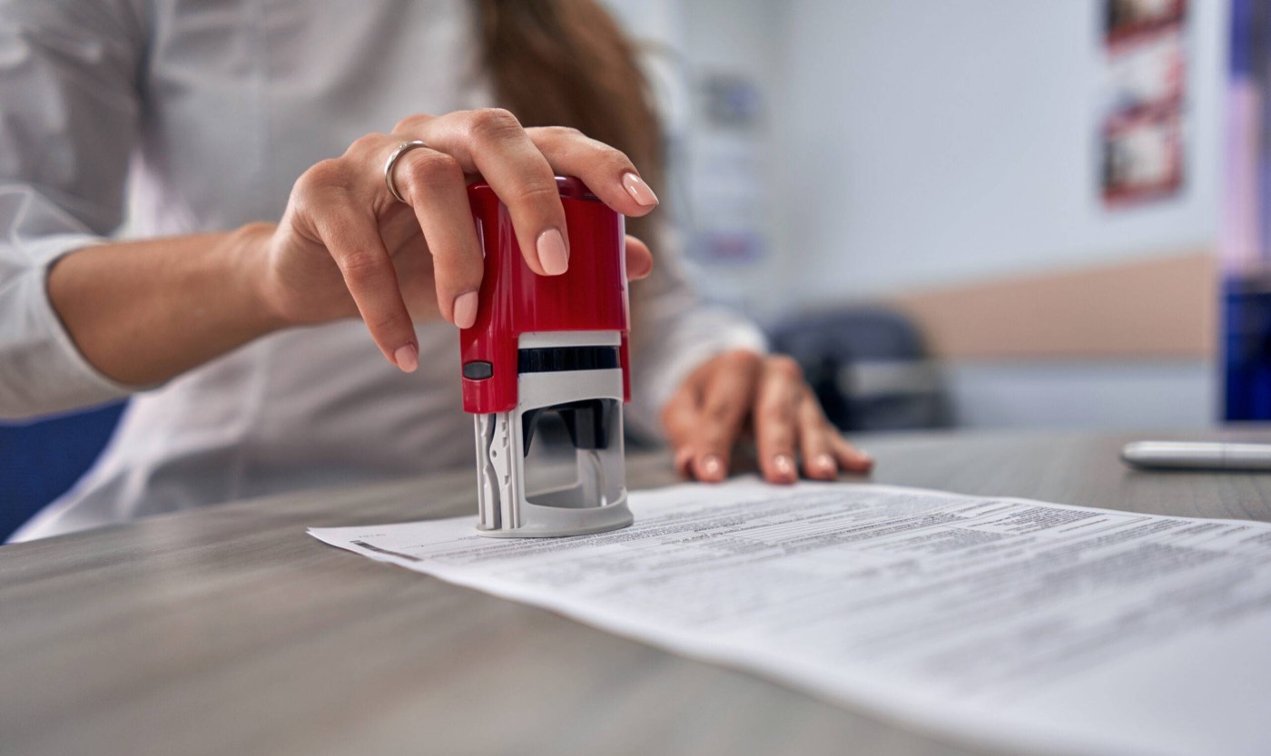 A notary public applying a seal to a document at a client's table
